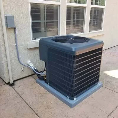 Black AC condenser unit on concrete pad with electrical line and refrigerant connections