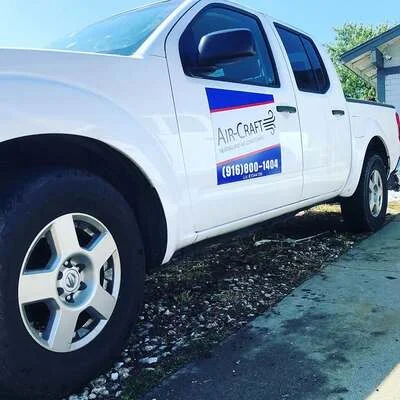 White HVAC service truck with blue company branding and contact number