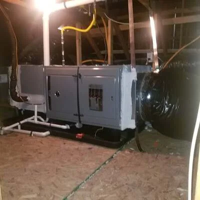 Commercial HVAC unit with ductwork and refrigerant lines on concrete mounting pad